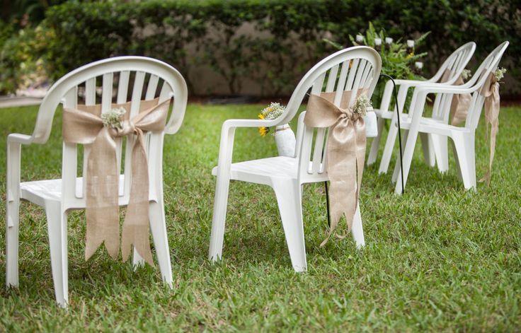 white chairs with bows tied to them in the grass