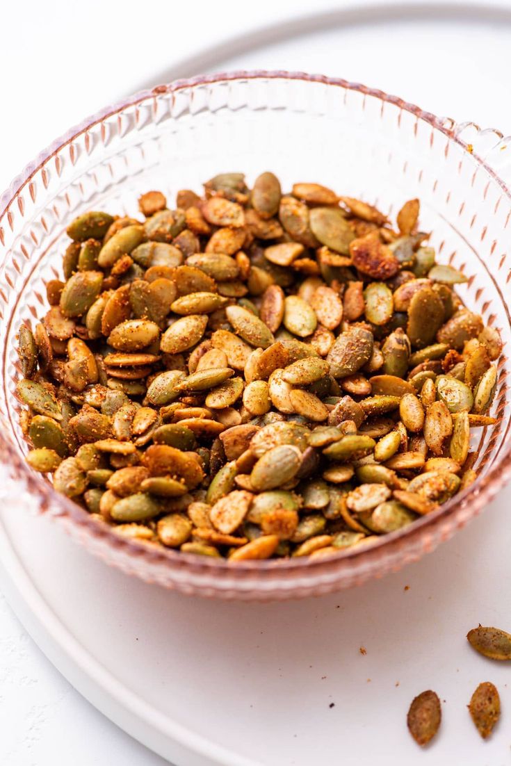 a glass bowl filled with nuts on top of a white plate