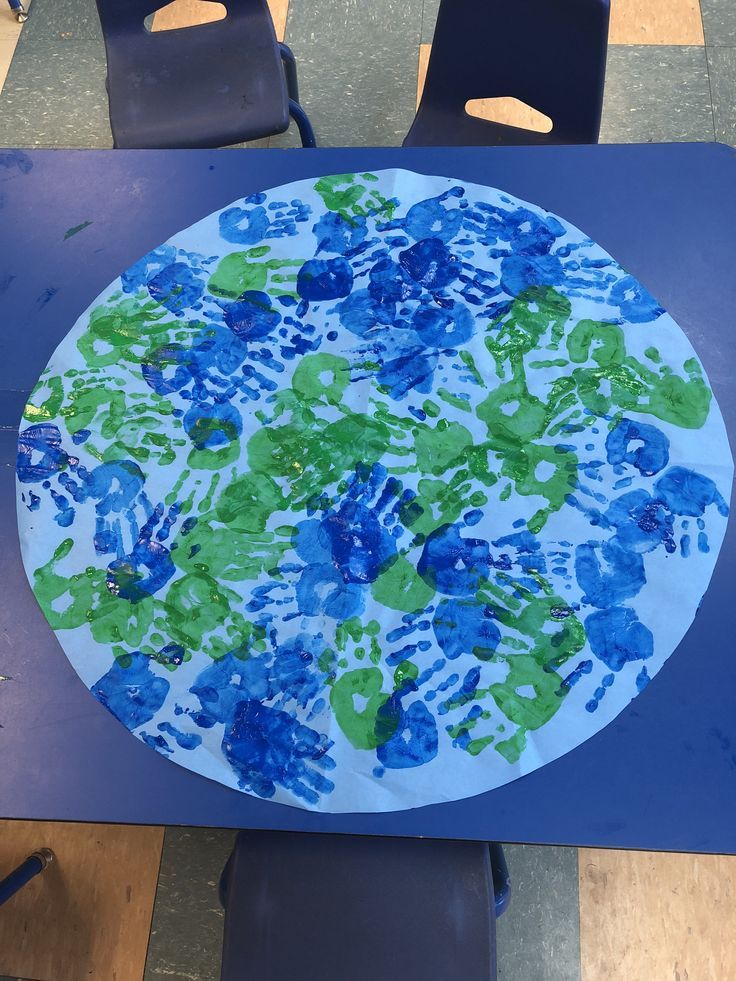 a paper plate with blue and green handprints sitting on top of a table