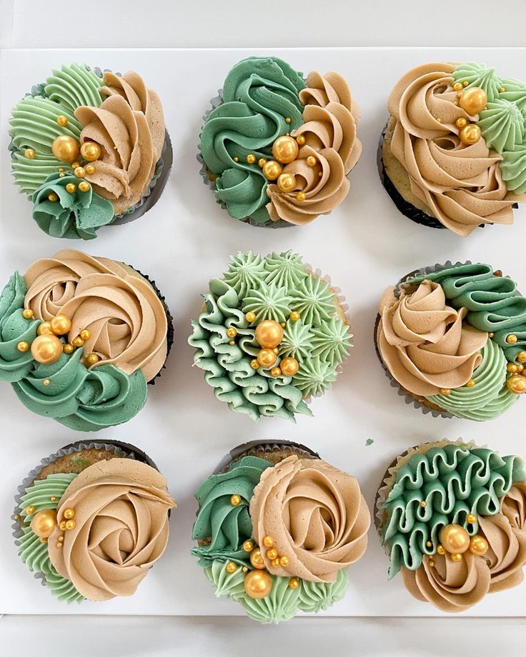 twelve cupcakes with green and brown frosting on a white tray, decorated with flowers