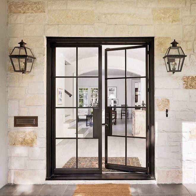 an open glass door leading to a living room with two lamps hanging on the wall