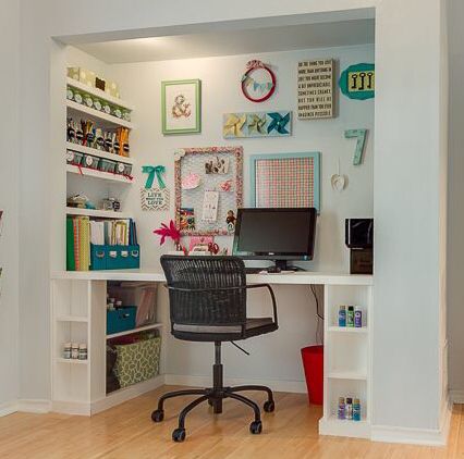 a desk with a computer on top of it in front of a wall filled with pictures