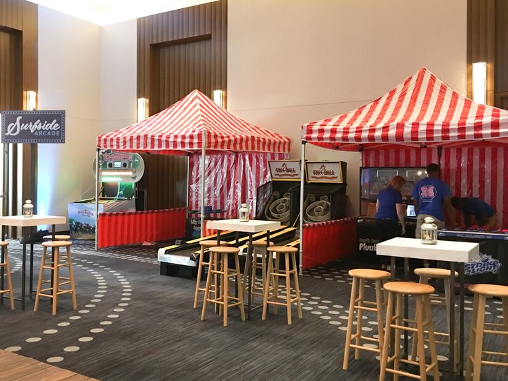 several tables and stools with red and white tents