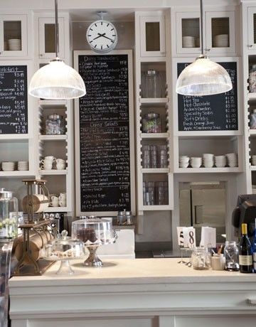 a kitchen with lots of white cabinets and counter top space next to a clock mounted on the wall