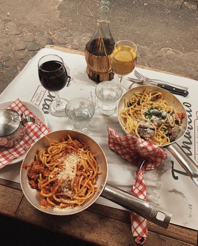 a table topped with plates of pasta and wine