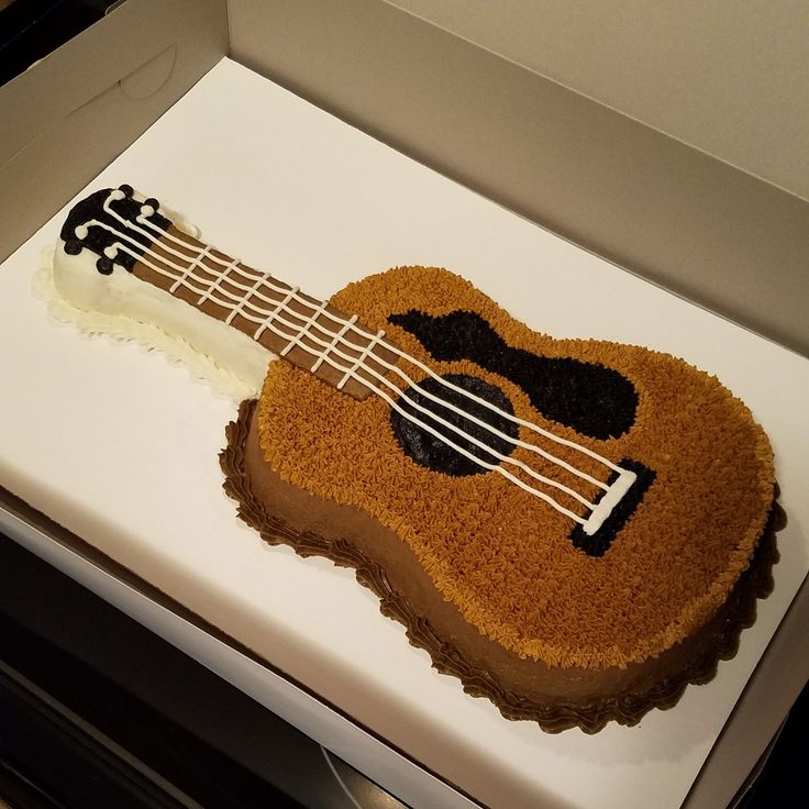 a cake shaped like an acoustic guitar on top of a white box with icing