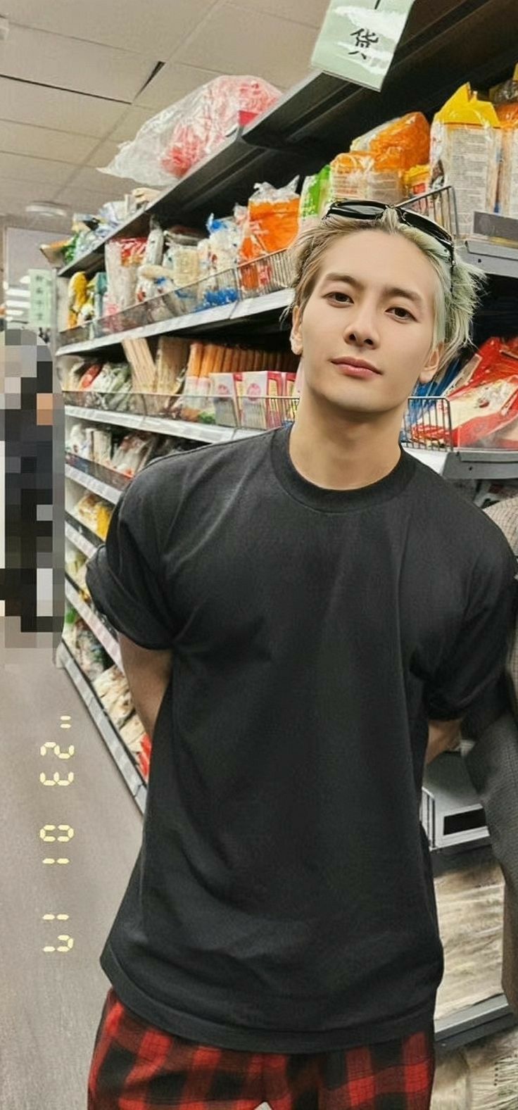 a young man standing in front of an empty grocery store shelf with his hand on the back of a bag