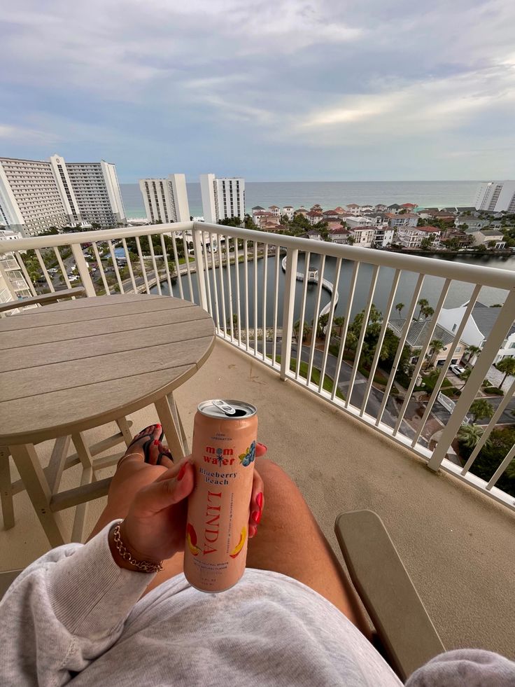 a person laying down on a balcony with a can of soda in front of them