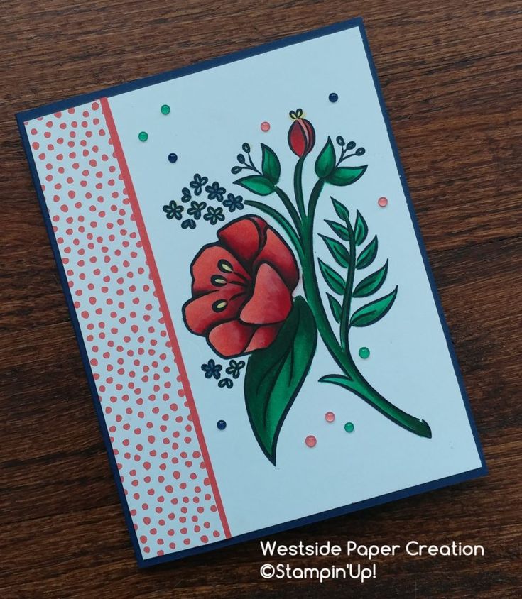 a close up of a card on a wooden table with flowers and leaves in it