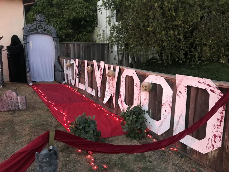 a wooden sign that says hollywood with lights around it and decorations on the fence behind it