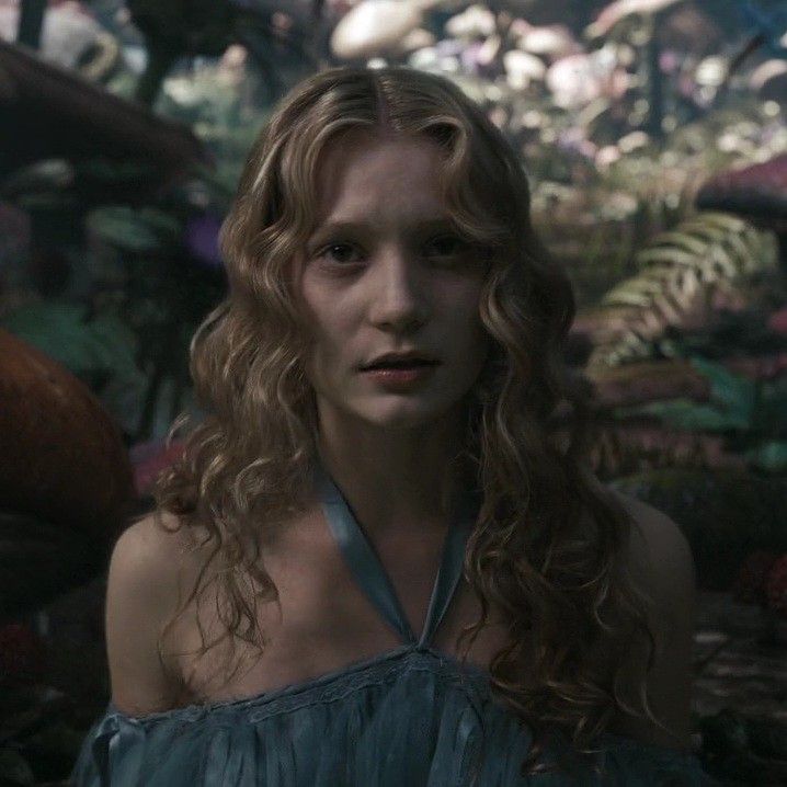 a woman with long curly hair wearing a blue dress and looking at something in the distance