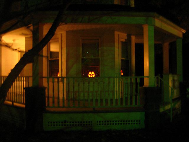 a house with halloween pumpkins on the front porch at night, lit up by candles