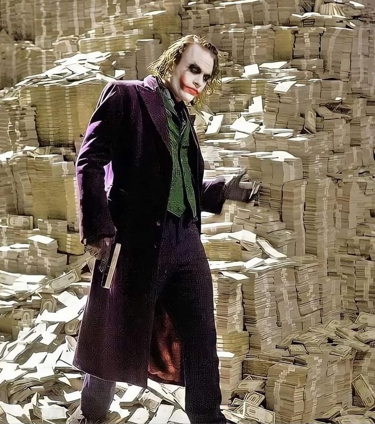 a man dressed as the joker standing in front of stacks of money