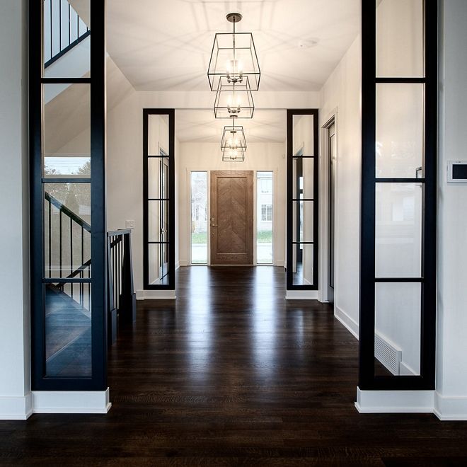 an empty hallway with black doors and white walls is seen in this image taken from the entry way