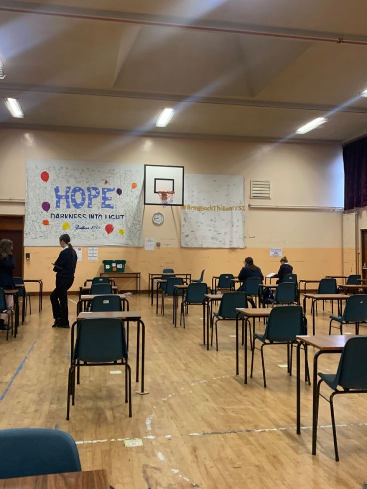 an empty classroom with desks and chairs in front of a large poster on the wall