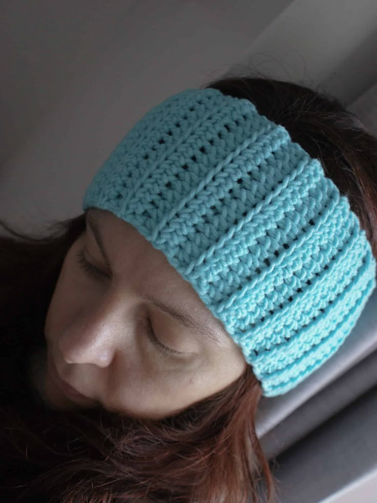 a woman wearing a blue crocheted headband with her eyes closed in front of the camera