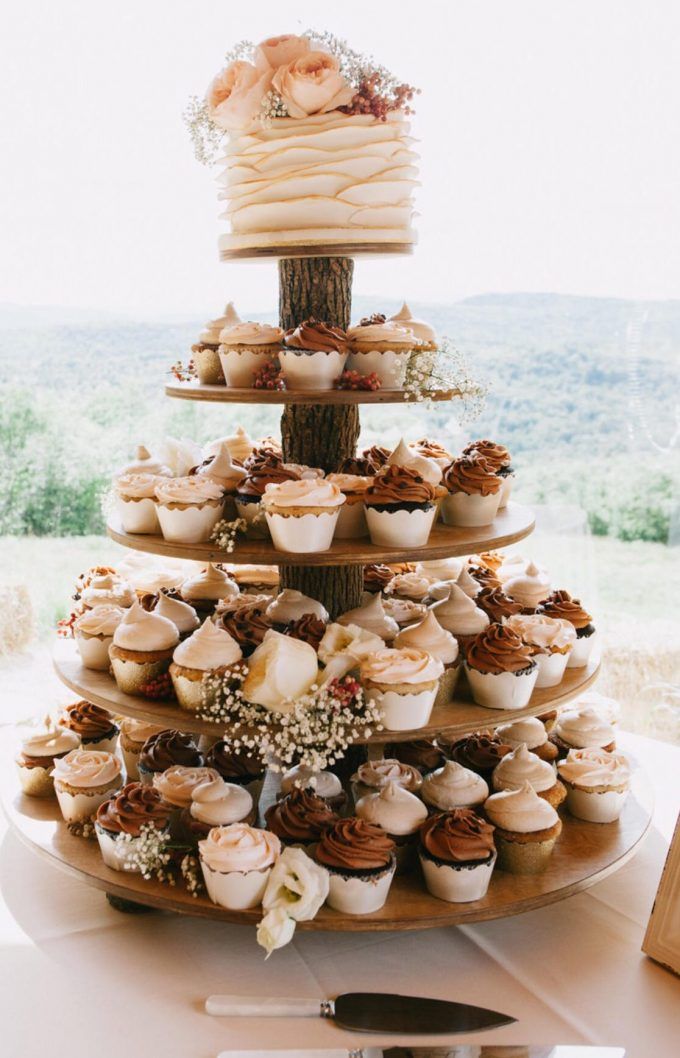 a three tiered cake with cupcakes on it