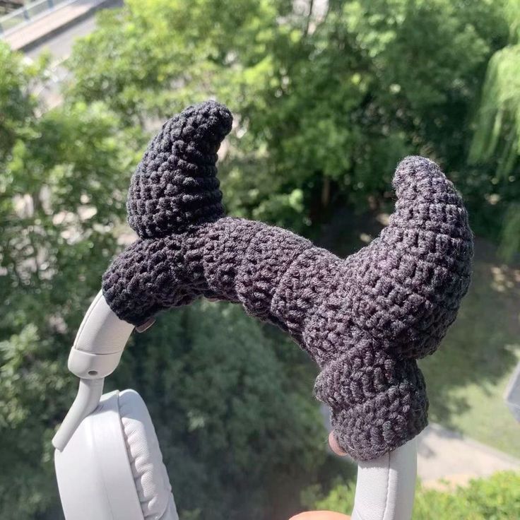 a hand holding a pair of headphones with a knitted animal on it's arm