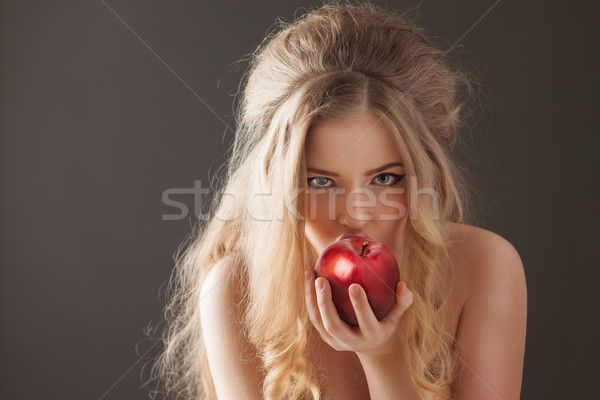 a beautiful blond woman holding an apple in her hand stock photo ©istoer / shutterstocker