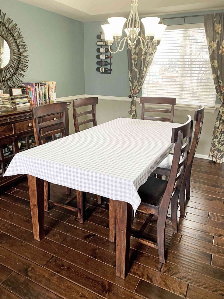 a dining room table and chairs with a checkered cloth on it, in front of a window