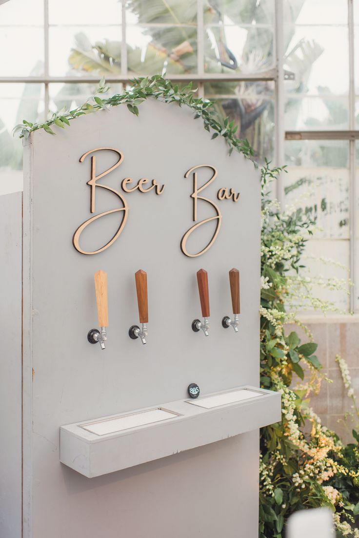 the beer tap sign is decorated with greenery and wooden pegs to hang on the wall