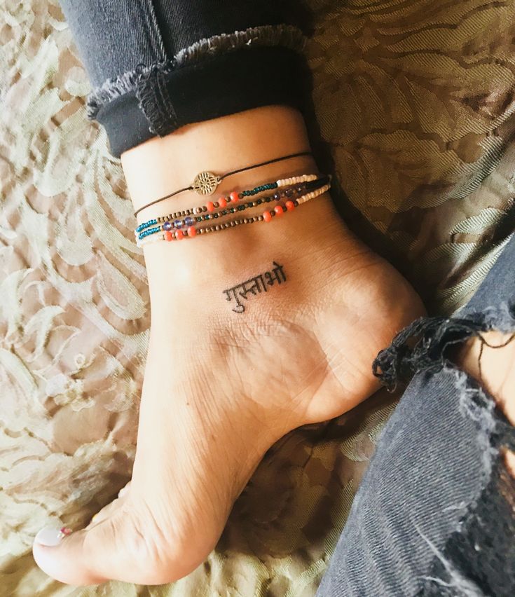 a woman's foot with two different bracelets on her ankles and one has a name tattooed on it