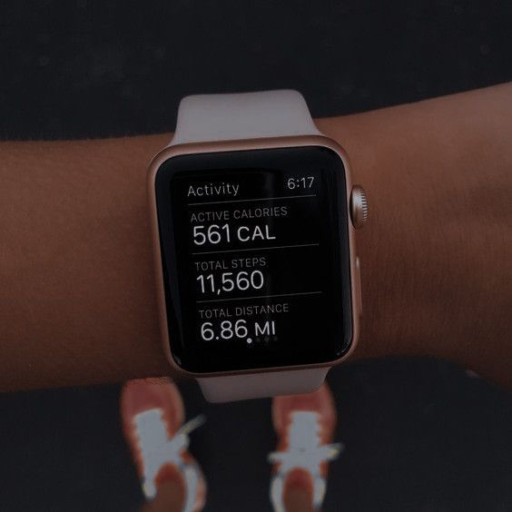 an apple watch displaying the time and activity on its wrist, with two hands holding it