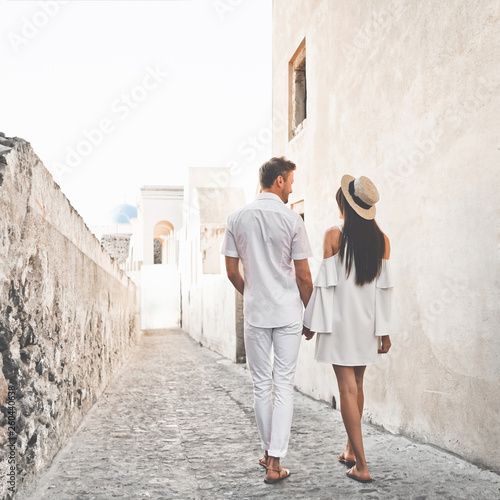 a man and woman walking down an alley way holding hands while looking at each other