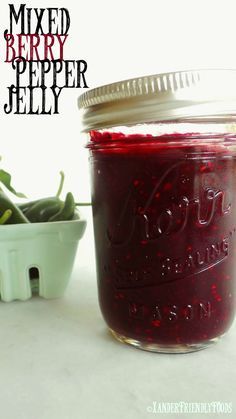 a jar filled with red liquid next to a bowl of green beans