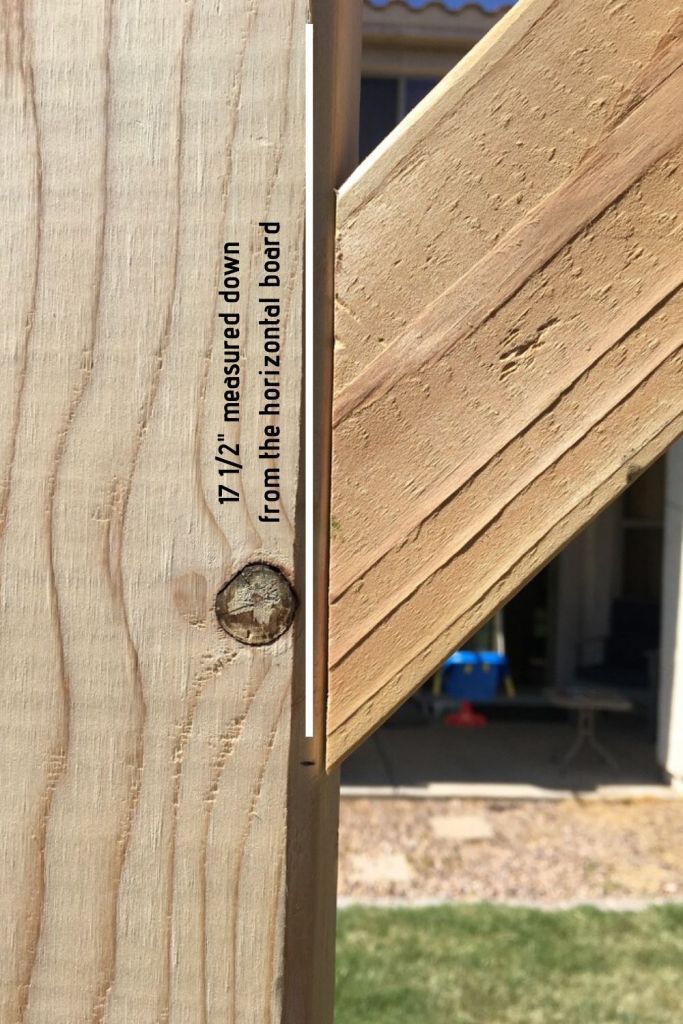 the side of a wooden structure with a screw in it's center and some grass behind it