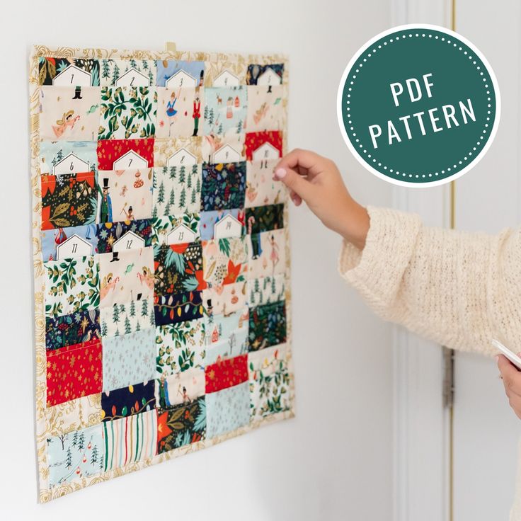 a woman is working on a quilted wall hanging