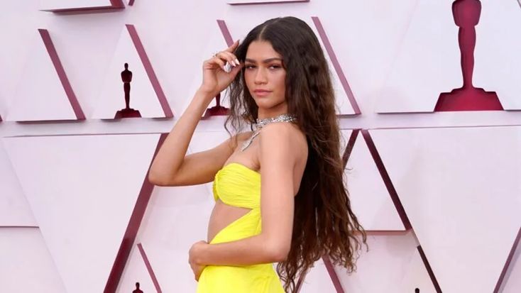 a woman in a yellow dress posing on the red carpet at an oscars event