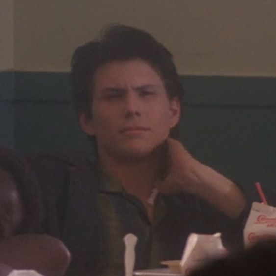 a man sitting at a table with food in front of him and looking off to the side