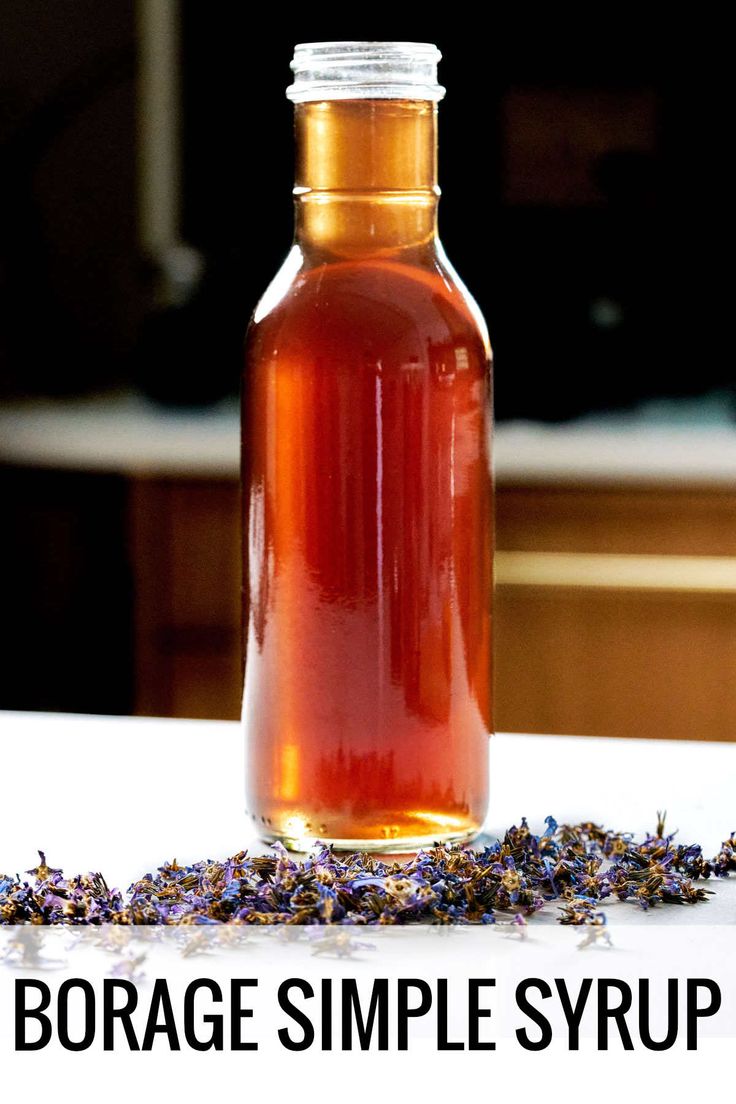 a bottle filled with liquid sitting on top of a table next to a pile of lavender