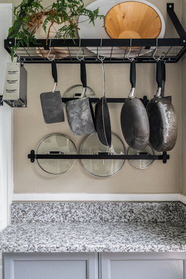 pots and pans are hanging on the wall in this kitchen with granite countertops