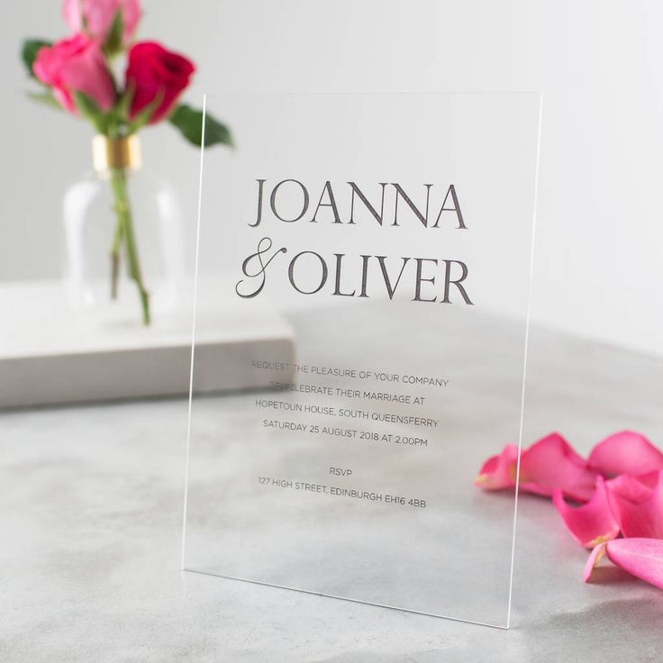 a clear acrylic sign with pink flowers on the table in front of it