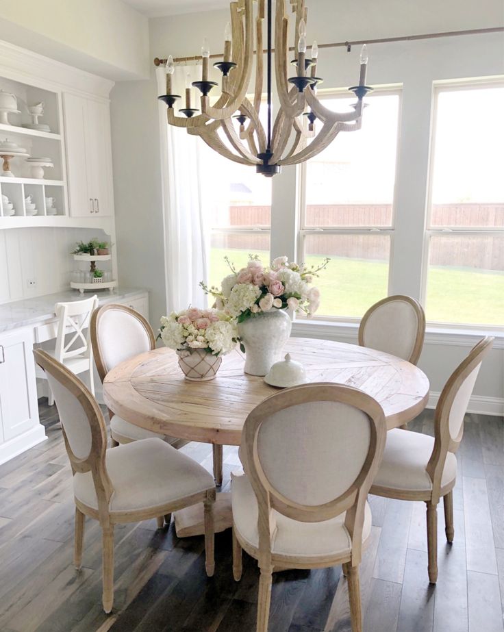 a dining room table with white chairs and a chandelier