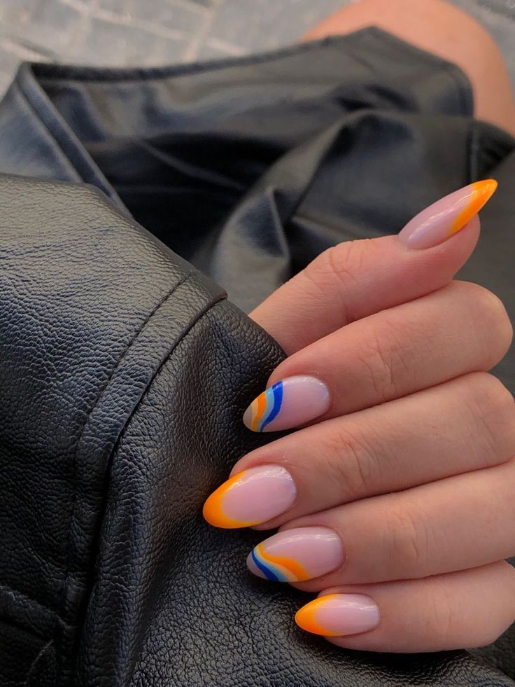 a woman's hand with orange, blue and yellow nail polish on her nails