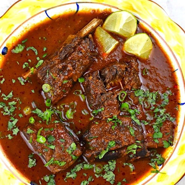 a bowl filled with meat and garnish on top of a yellow table cloth