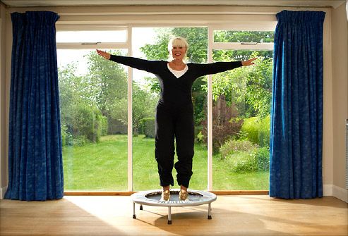 an older woman standing on top of a trampoline in front of a window