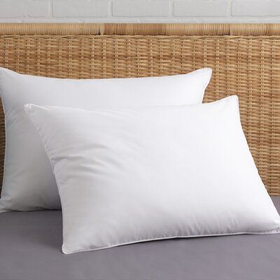 two white pillows sitting on top of a bed next to a headboard with a brick wall in the background