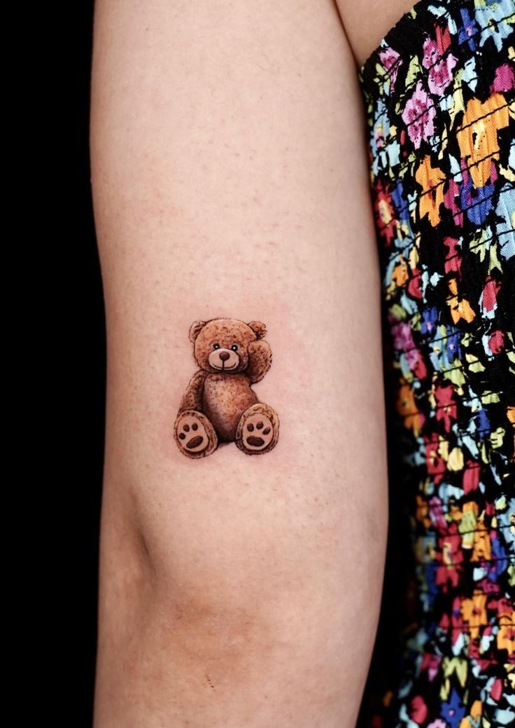 a small teddy bear tattoo on the left arm