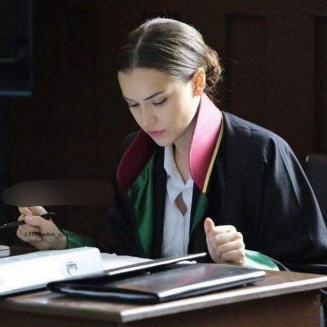 a woman sitting at a desk with a book and pen in her hand, writing