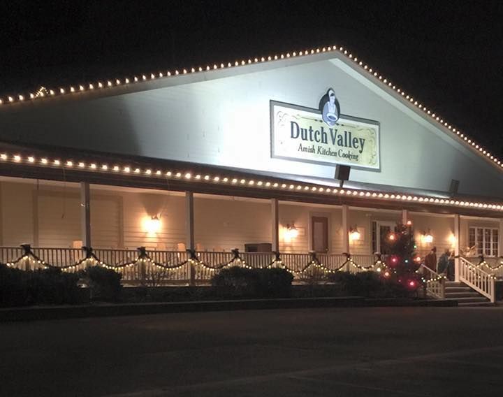 the exterior of dutch valley motel lit up at night with christmas lights and decorations on the front porch