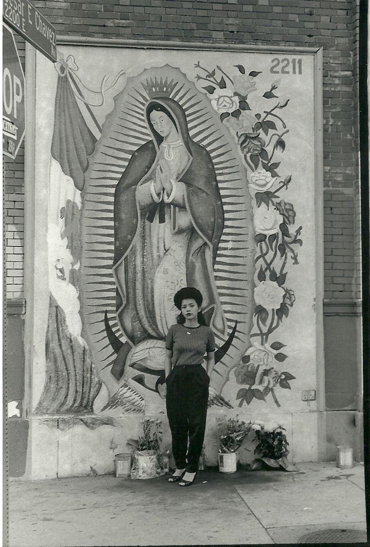 a woman standing in front of a painting on the side of a building