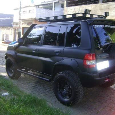 a black suv parked on the side of a road next to a brick walkway and building