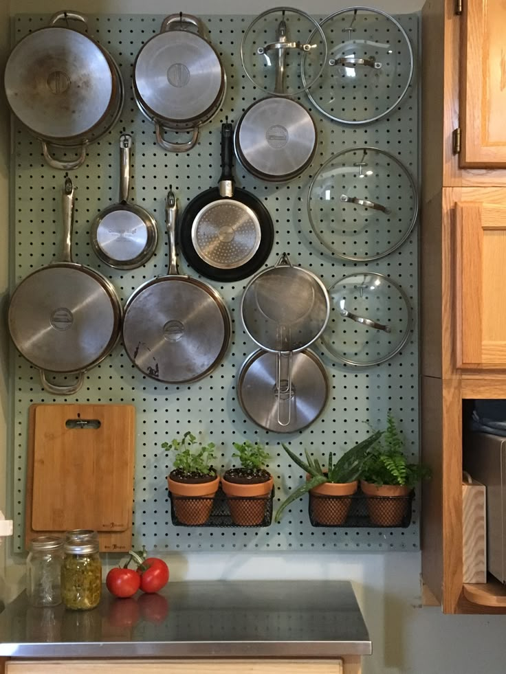 pots and pans are hanging on a pegboard in a kitchen area with wooden cabinets