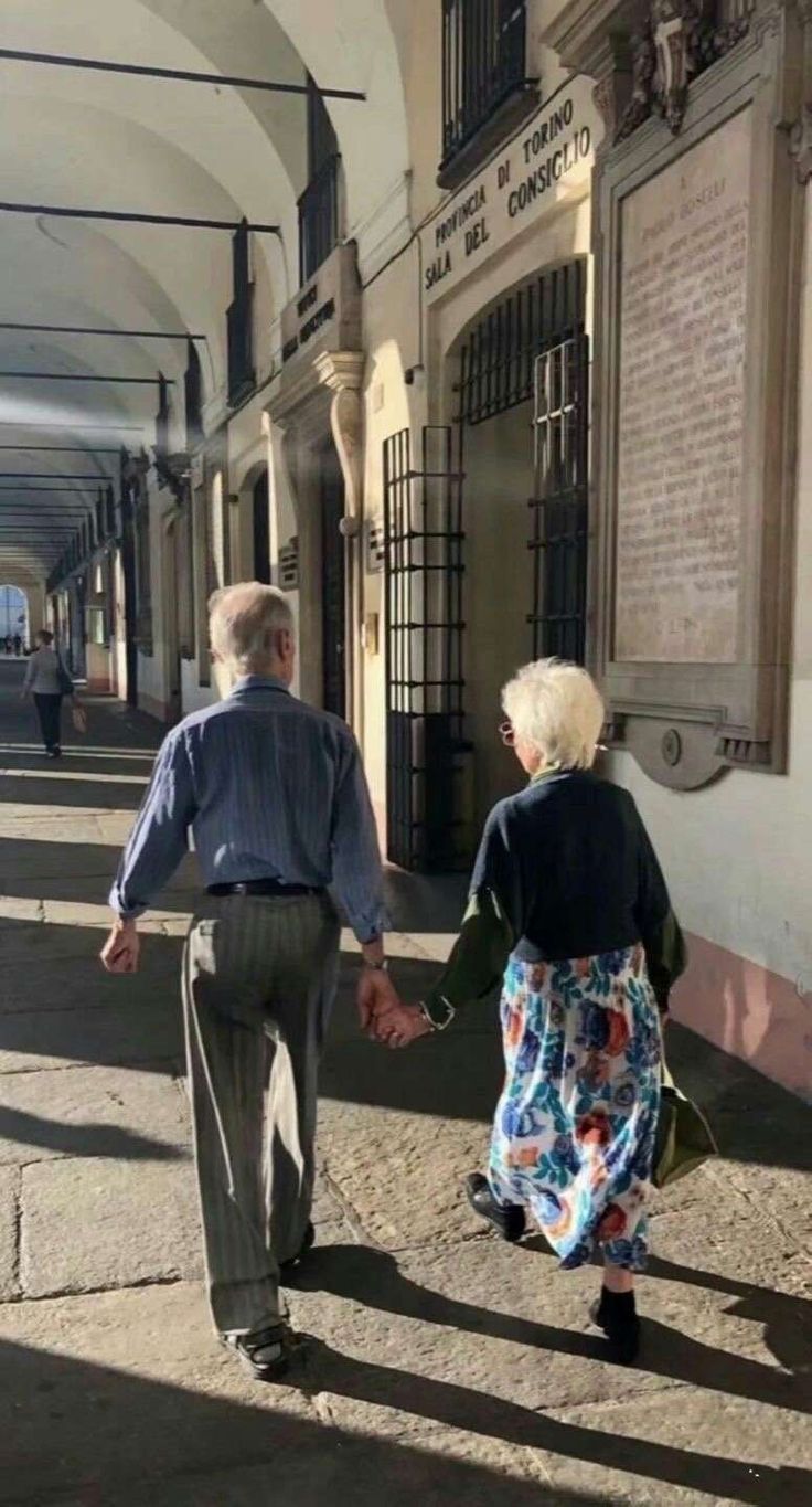 an older couple walking down the street holding hands