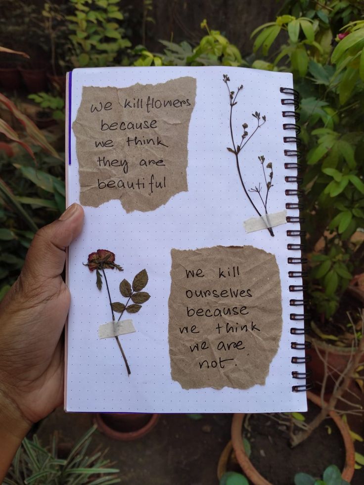 someone is holding up a notebook with some writing on it and there are flowers in the pages