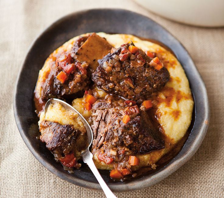 a bowl filled with meat and potatoes on top of a table